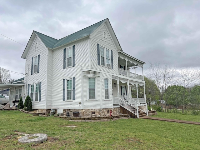 view of front facade featuring a balcony, metal roof, and a front yard