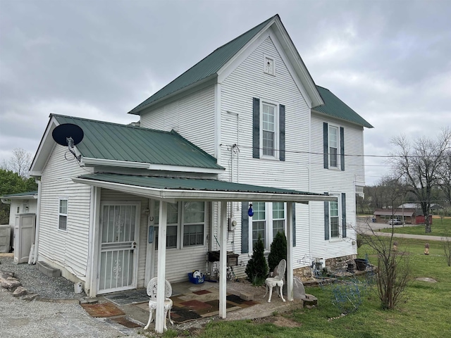 rear view of property with a lawn and metal roof