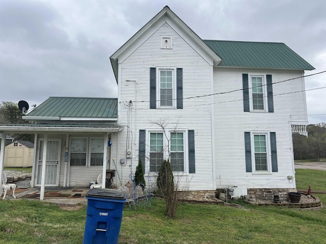view of front of home with metal roof and a front lawn