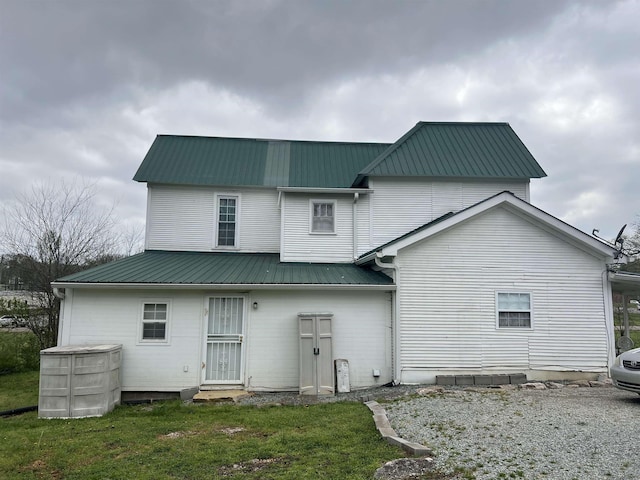 rear view of property featuring a lawn and metal roof