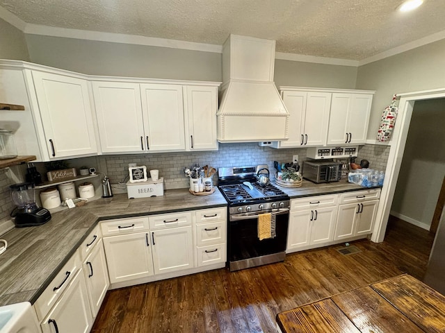 417 E Tigrett St, Halls, TN 38040 - kitchen featuring white cabinets, custom exhaust hood, dark countertops, dark wood-style floors, and stainless steel gas stove