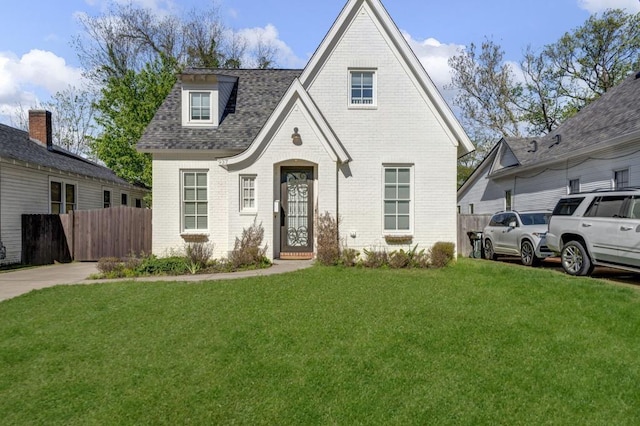 view of front of home featuring brick siding, a front yard, a shingled roof, and fence