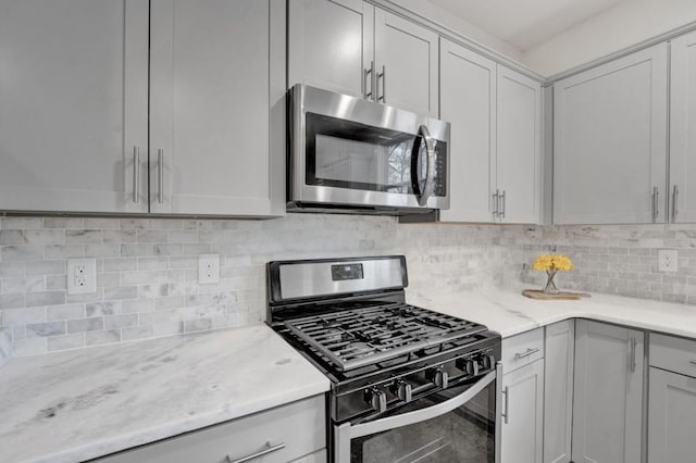 kitchen featuring light stone countertops, backsplash, and appliances with stainless steel finishes