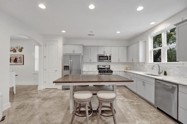 kitchen with visible vents, appliances with stainless steel finishes, arched walkways, a sink, and a kitchen breakfast bar