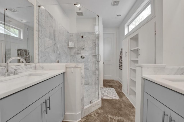 full bathroom featuring a stall shower, visible vents, a sink, and two vanities