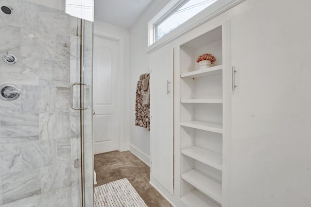 bathroom with a stall shower and built in shelves