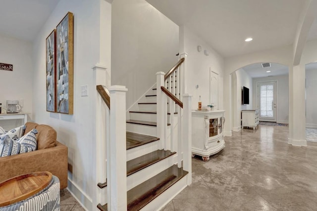 staircase featuring arched walkways, visible vents, baseboards, and recessed lighting