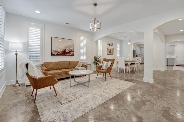living area featuring arched walkways, baseboards, and recessed lighting