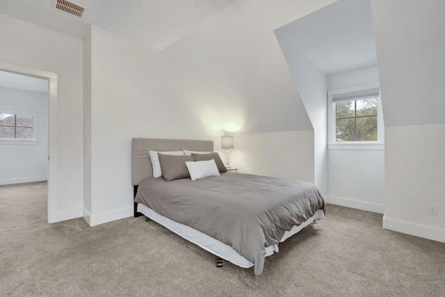 carpeted bedroom featuring baseboards, visible vents, and lofted ceiling