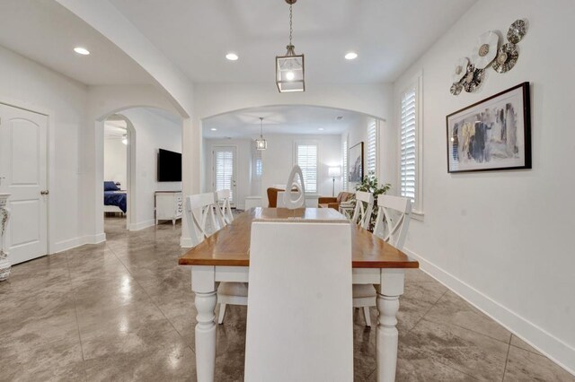 dining room with baseboards, arched walkways, and recessed lighting