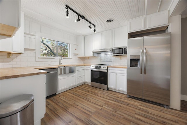 kitchen with a sink, open shelves, appliances with stainless steel finishes, wooden counters, and under cabinet range hood