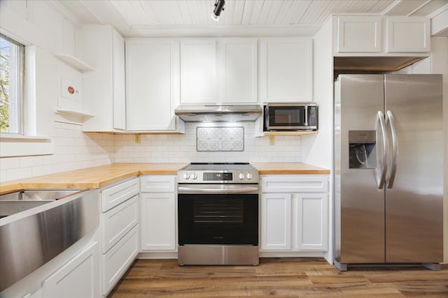kitchen featuring stainless steel appliances, under cabinet range hood, wood counters, light wood-style floors, and white cabinets
