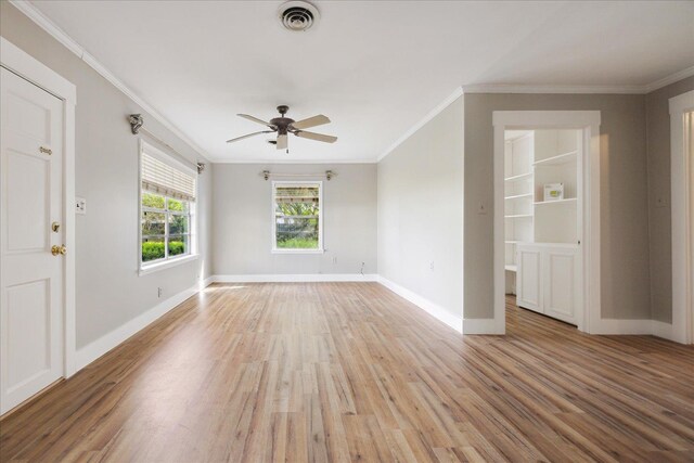 spare room with light wood finished floors, visible vents, crown molding, and a ceiling fan