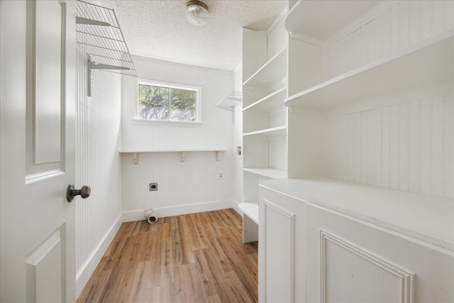 washroom with light wood-type flooring, baseboards, a textured ceiling, electric dryer hookup, and laundry area