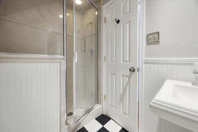 full bathroom featuring a stall shower, tile patterned floors, a sink, and a wainscoted wall