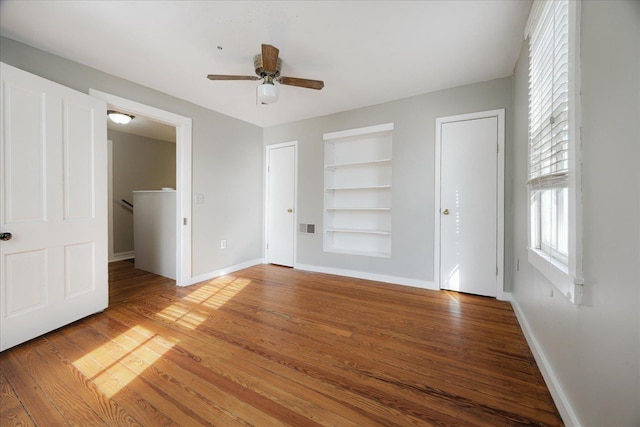 unfurnished bedroom featuring visible vents, two closets, baseboards, ceiling fan, and light wood-style floors