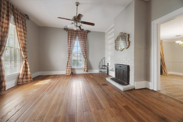 unfurnished living room with hardwood / wood-style floors, a ceiling fan, baseboards, and built in shelves
