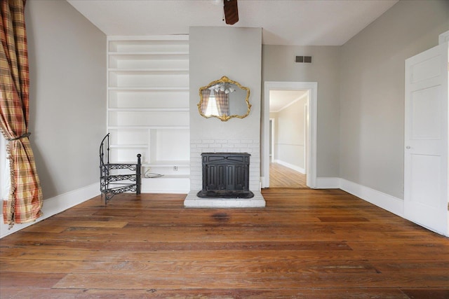 unfurnished living room with baseboards, built in shelves, visible vents, and wood-type flooring