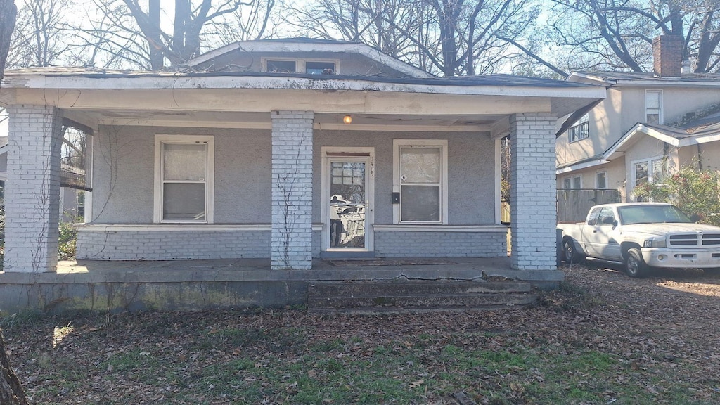 view of front of house with covered porch, brick siding, and stucco siding