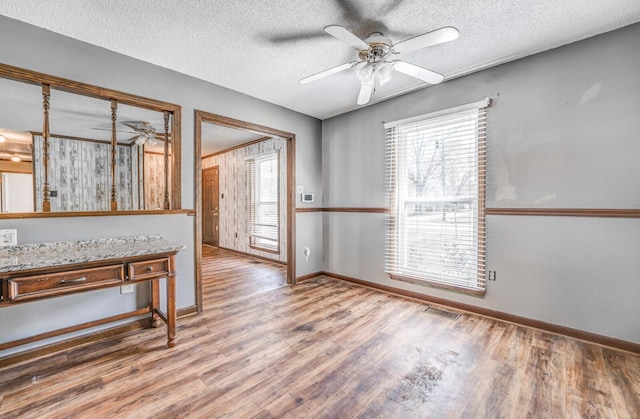 interior space with a textured ceiling, visible vents, a ceiling fan, and wood finished floors