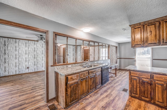 kitchen with visible vents, baseboards, wood finished floors, a sink, and light stone counters