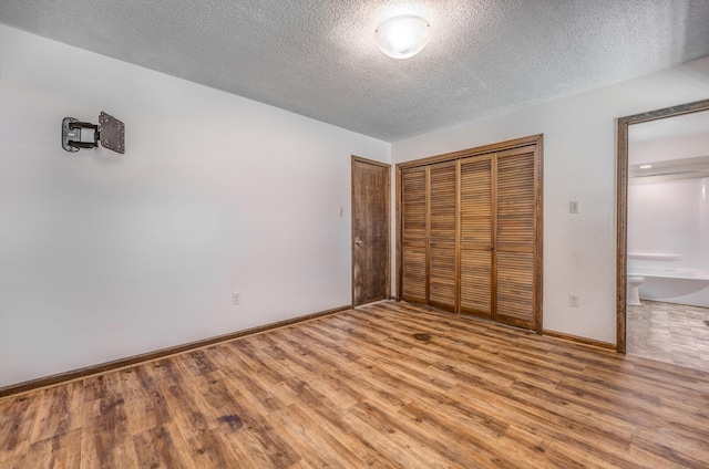 unfurnished bedroom featuring light wood-style floors, baseboards, a closet, and a textured ceiling