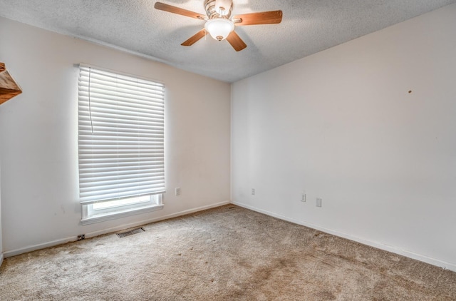 empty room with carpet flooring, a textured ceiling, visible vents, baseboards, and a ceiling fan