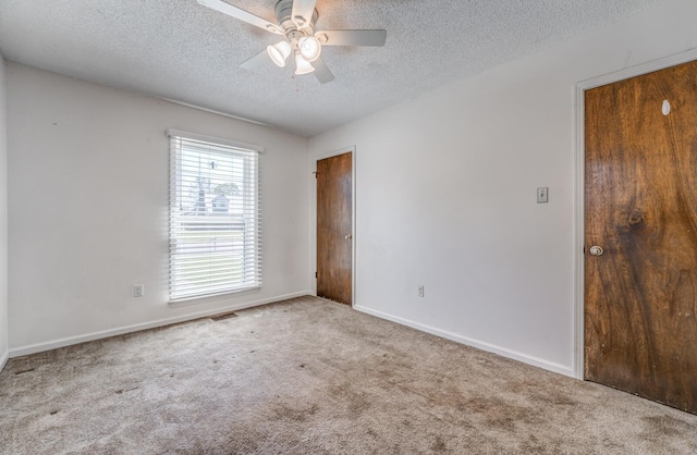 unfurnished room with carpet floors, a textured ceiling, baseboards, visible vents, and ceiling fan