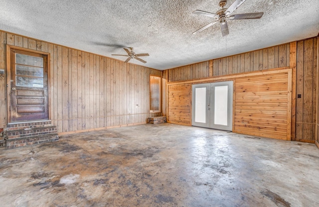 unfurnished room with a textured ceiling, concrete floors, ceiling fan, and french doors