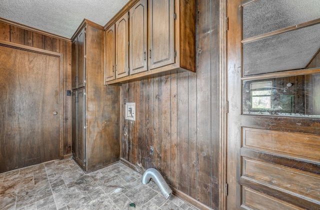 laundry area with washer hookup, wood walls, and a textured ceiling