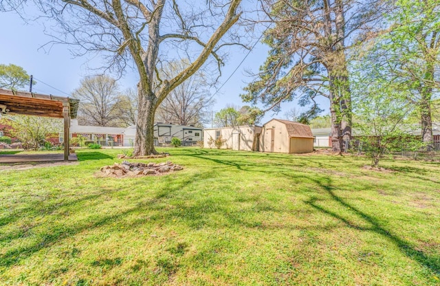 view of yard with an outbuilding, fence, and a storage shed