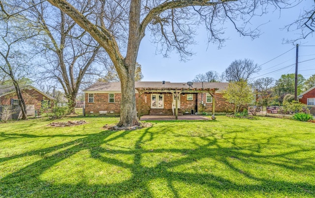 rear view of property with brick siding, fence, and a yard