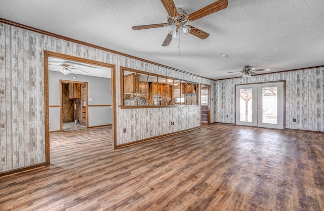 unfurnished living room featuring ceiling fan, wood finished floors, and ornamental molding