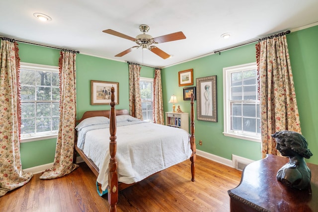 bedroom featuring multiple windows, crown molding, wood finished floors, and baseboards