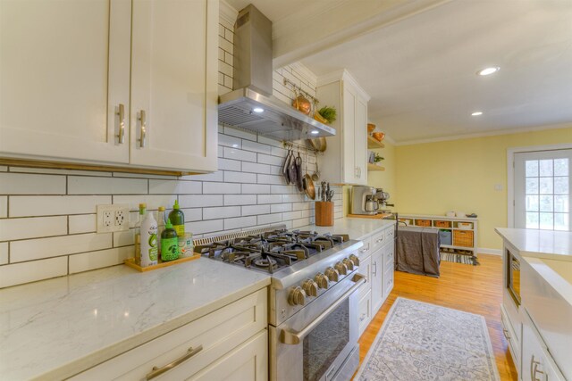 26 N Ashlawn Dr, Memphis, TN 38112 - kitchen with ornamental molding, island exhaust hood, high end stove, decorative backsplash, and light wood-style flooring