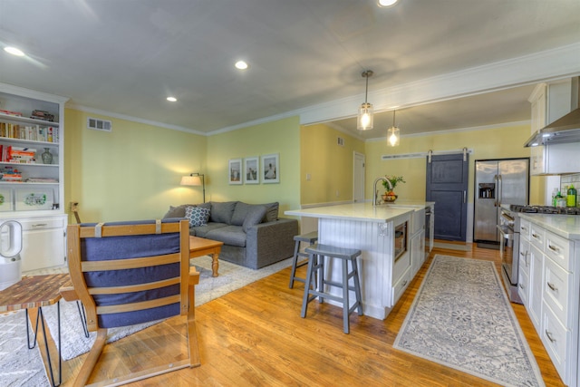 26 N Ashlawn Dr, Memphis, TN 38112 - kitchen featuring visible vents, a kitchen island with sink, appliances with stainless steel finishes, a barn door, and white cabinetry
