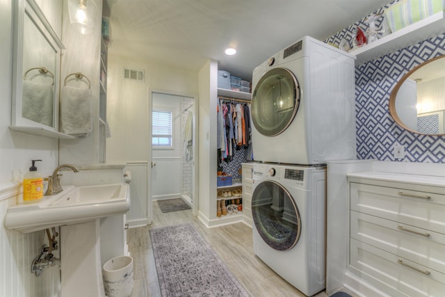 26 N Ashlawn Dr, Memphis, TN 38112 - laundry area featuring wallpapered walls, stacked washing maching and dryer, light wood-type flooring, laundry area, and visible vents