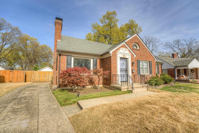 26 N Ashlawn Dr, Memphis, TN 38112 - bungalow-style home featuring roof with shingles, fence, a front lawn, brick siding, and a chimney