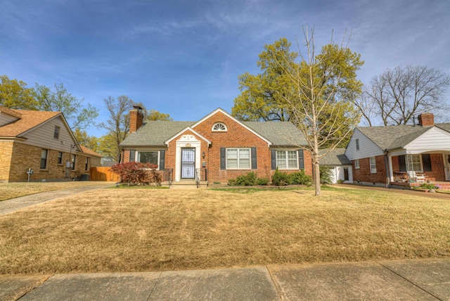 26 N Ashlawn Dr, Memphis, TN 38112 - view of front facade with a chimney, brick siding, roof with shingles, and a front lawn