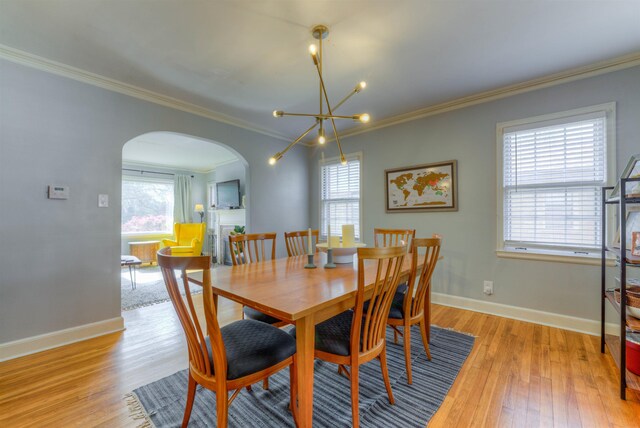 26 N Ashlawn Dr, Memphis, TN 38112 - dining space with arched walkways, baseboards, an inviting chandelier, and light wood-style floors