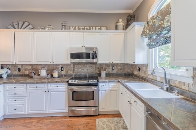 1249 Mintmere Dr, Collierville, TN 38017 - kitchen featuring stainless steel appliances, white cabinetry, light wood finished floors, ornamental molding, and backsplash