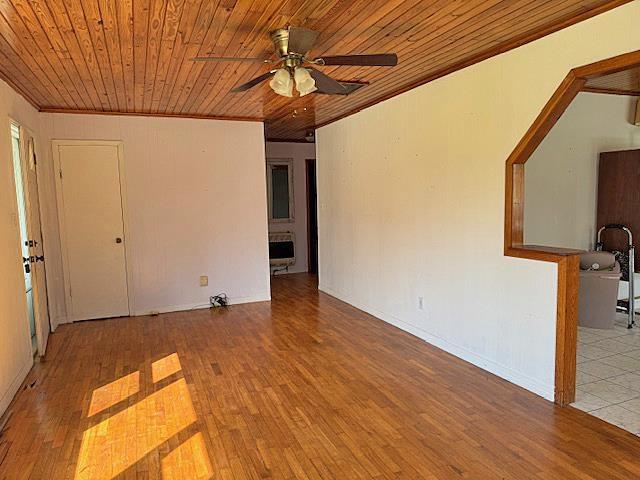 unfurnished room featuring a ceiling fan, wood ceiling, crown molding, and wood finished floors