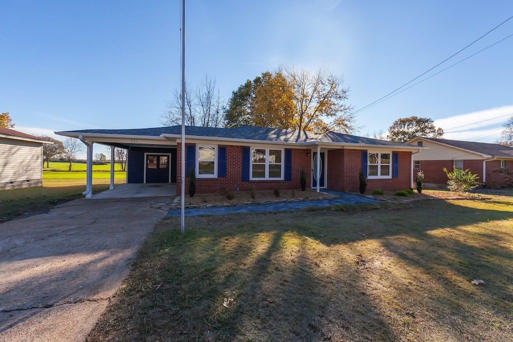 ranch-style home featuring an attached carport, a front yard, brick siding, and driveway