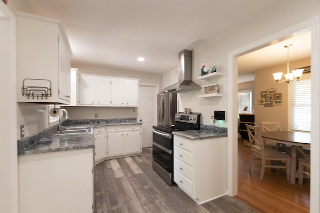 kitchen featuring an inviting chandelier, wall chimney exhaust hood, a sink, appliances with stainless steel finishes, and dark countertops