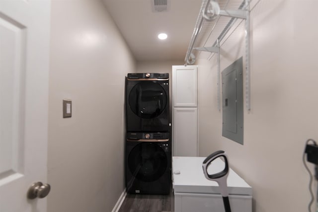 washroom featuring visible vents, baseboards, electric panel, stacked washing maching and dryer, and cabinet space