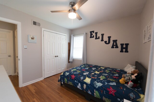 bedroom with visible vents, baseboards, a closet, ceiling fan, and wood finished floors