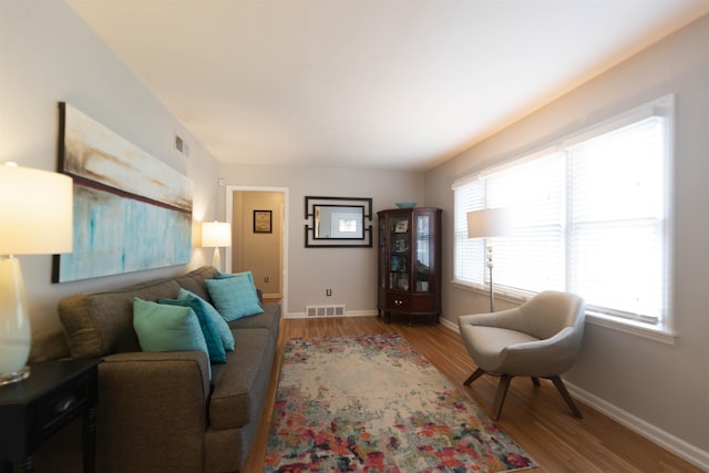 living area featuring visible vents, baseboards, and wood finished floors
