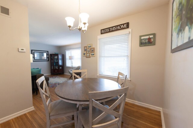 dining space featuring visible vents, baseboards, an inviting chandelier, and wood finished floors