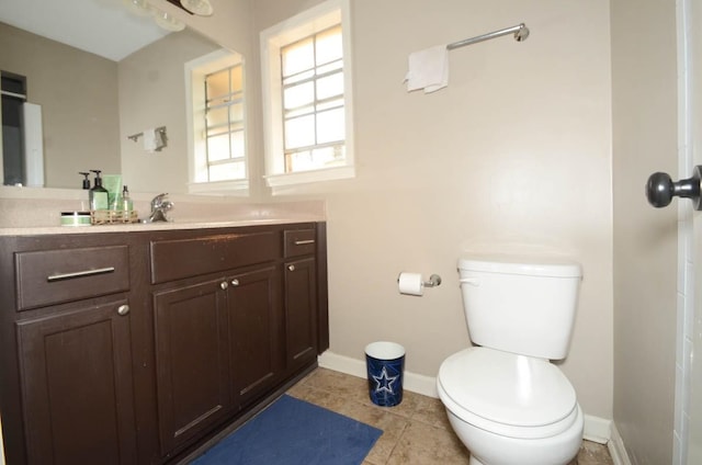 bathroom with tile patterned flooring, vanity, baseboards, and toilet