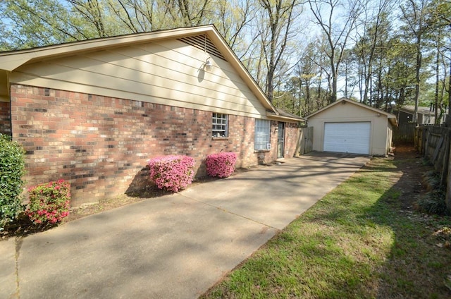 view of side of property featuring an outbuilding, a garage, fence, brick siding, and concrete driveway